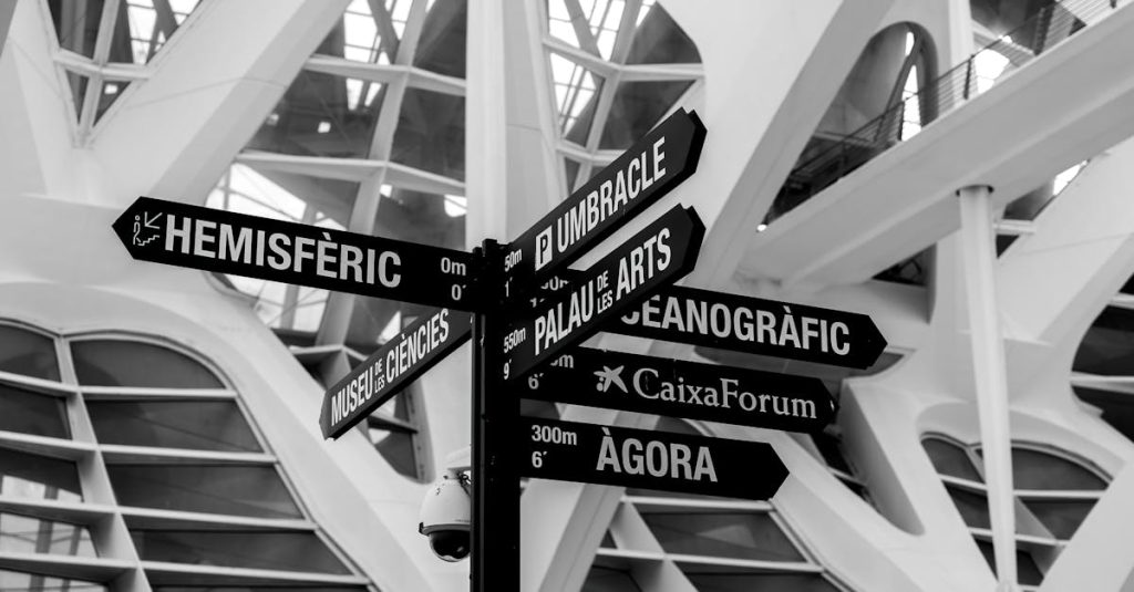 Black and white image of a signpost in the City of Arts and Sciences, Valencia, highlighting its modern architecture.